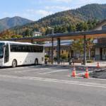 A tour coach beside a small coned-off parking work area at a Japanese station