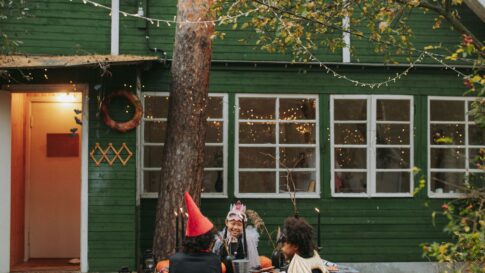 Children in Halloween costumes gathering outdoors with pumpkins and autumn decorations