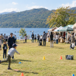 Families enjoying a ball game, stage, and market stalls beside Lake Yamanaka