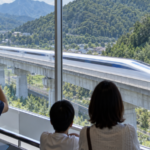 Visitors watching a high-speed maglev test train from an indoor observation gallery